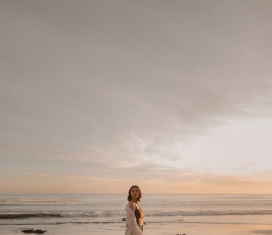 마이 바레 자격증 최고의 선택 Woman stands on rocks at the beach during sunset.