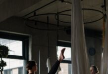 헬스와는 전혀 다른 바레 운동 A woman practices barre exercises in a yoga studio with mirrors and hanging fabric.