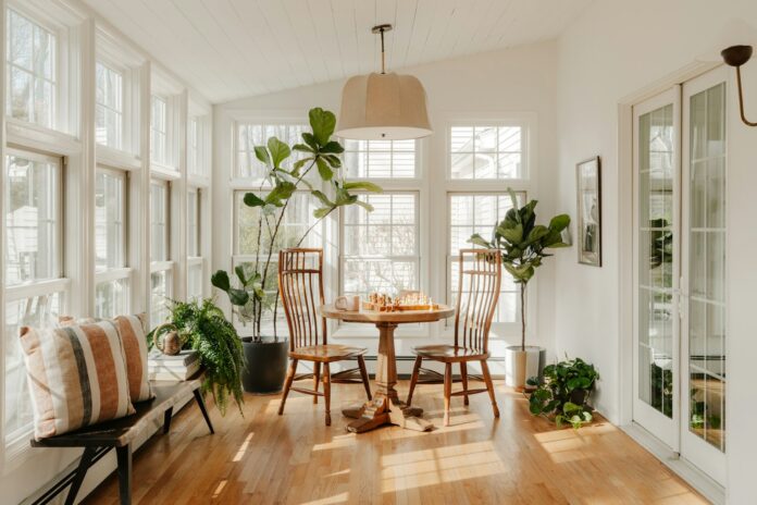 Photo by Clay Banks Bright sunroom with plants and dining table.
