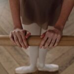 바레 자격증, 따라 하는 강사가 아닌 만드는 강사가 되세요 A young ballet dancer in uniform practicing at a barre inside a dance studio.