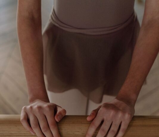 바레 자격증, 따라 하는 강사가 아닌 만드는 강사가 되세요 A young ballet dancer in uniform practicing at a barre inside a dance studio.