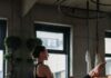 바레 자격증 비용보다 더 중요한 것은 ‘교육 이후’입니다 A woman performs a yoga stretch in a modern studio setting, focusing on flexibility and balance.