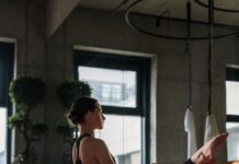 바레 자격증 비용보다 더 중요한 것은 ‘교육 이후’입니다 A woman performs a yoga stretch in a modern studio setting, focusing on flexibility and balance.