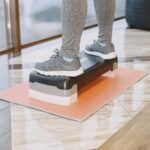 스텝박스 자격증, 왜 민트리온이 요즘 트렌드일까요? A person exercising indoors using a step platform for a workout routine.