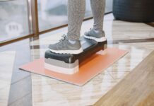 스텝박스 자격증, 왜 민트리온이 요즘 트렌드일까요? A person exercising indoors using a step platform for a workout routine.