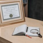 좋은 강사는 자격증 개수로 결정되지 않습니다 Open notebook with magnifying glass on wooden table beside framed certificate.