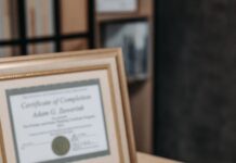 좋은 강사는 자격증 개수로 결정되지 않습니다 Open notebook with magnifying glass on wooden table beside framed certificate.