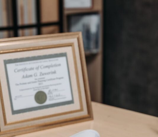 좋은 강사는 자격증 개수로 결정되지 않습니다 Open notebook with magnifying glass on wooden table beside framed certificate.
