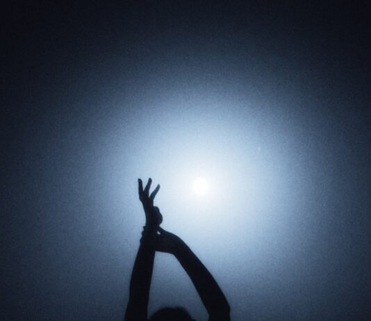 바레 동작 100개 외워도 소용없습니다|회원의 몸을 바꾸는 건 따로 있습니다 A person in silhouette with arms raised against a bright blue light